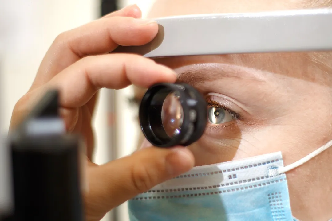 Ophthalmologist examining a patient's retina with a slit-lamp lens